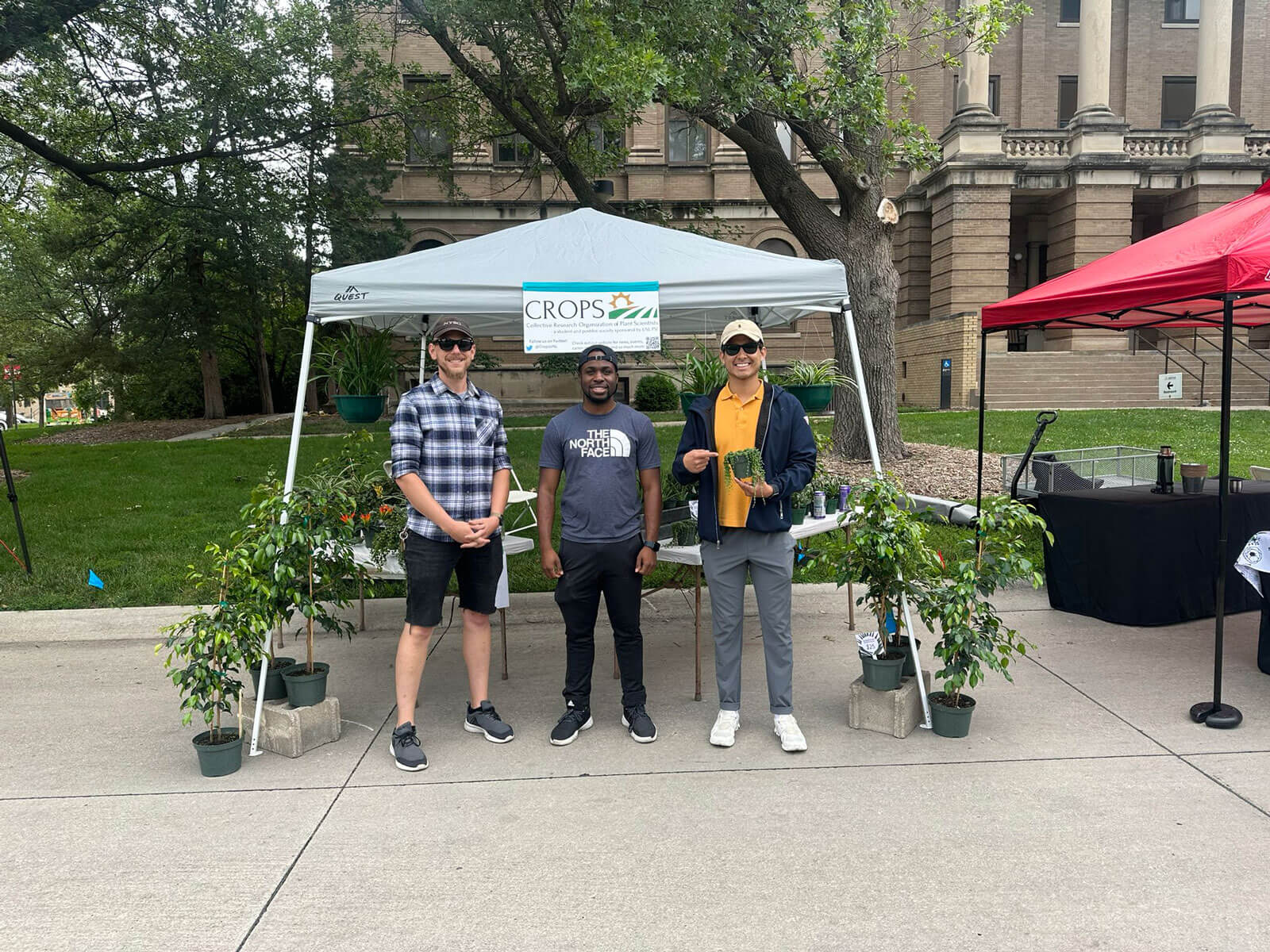 A group of people standing in front of a plant sale booth on East Campus