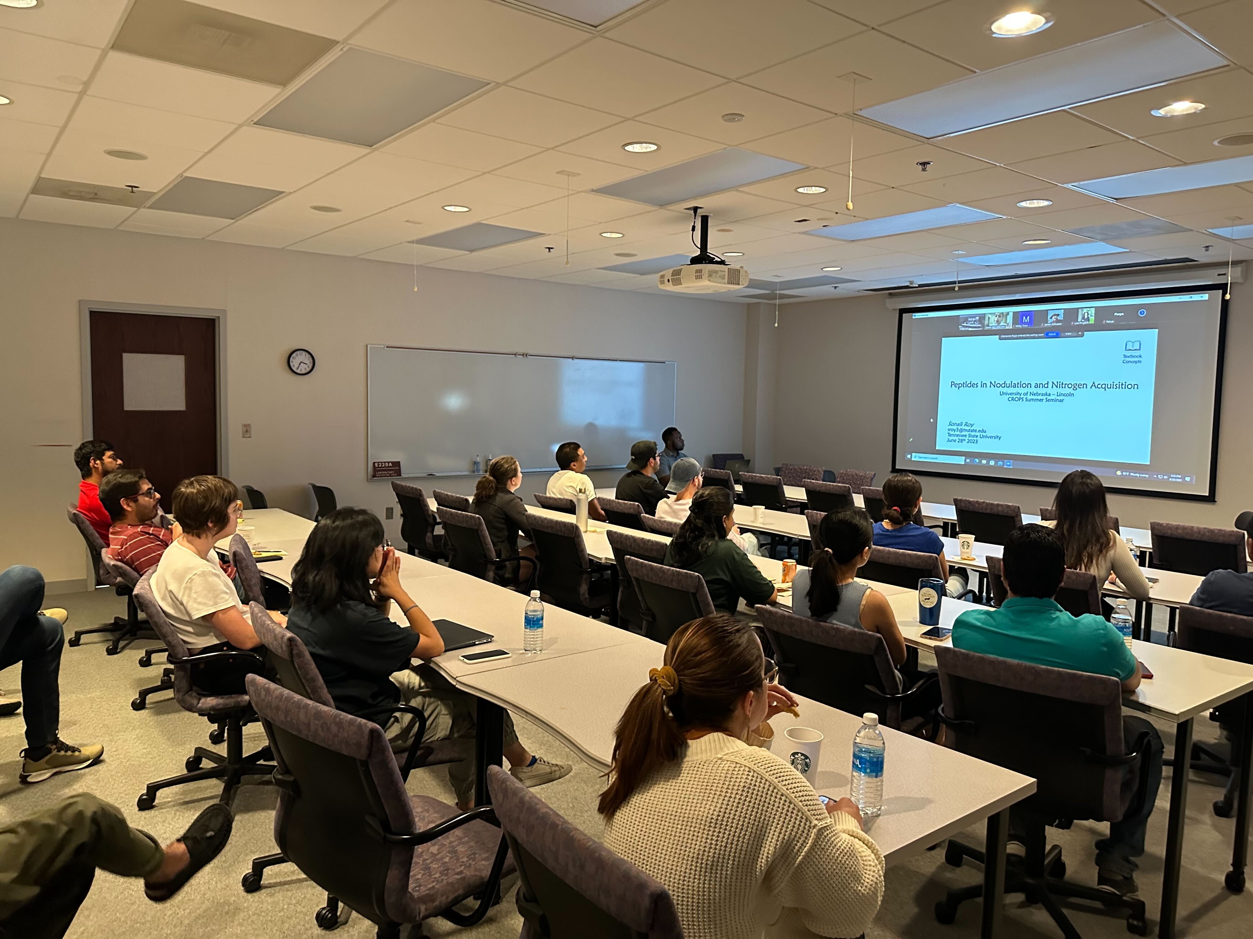 A group of people watching a research presentation in a classroom