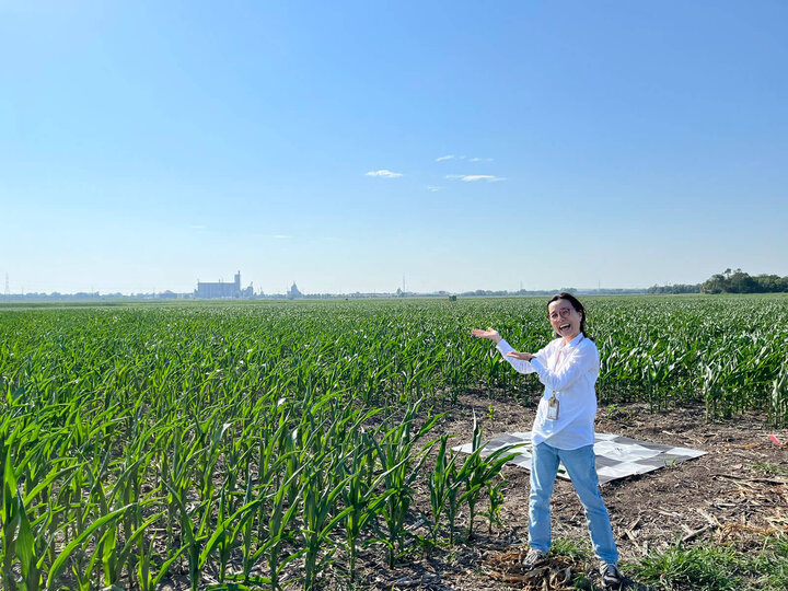 A woman next to a corn field.