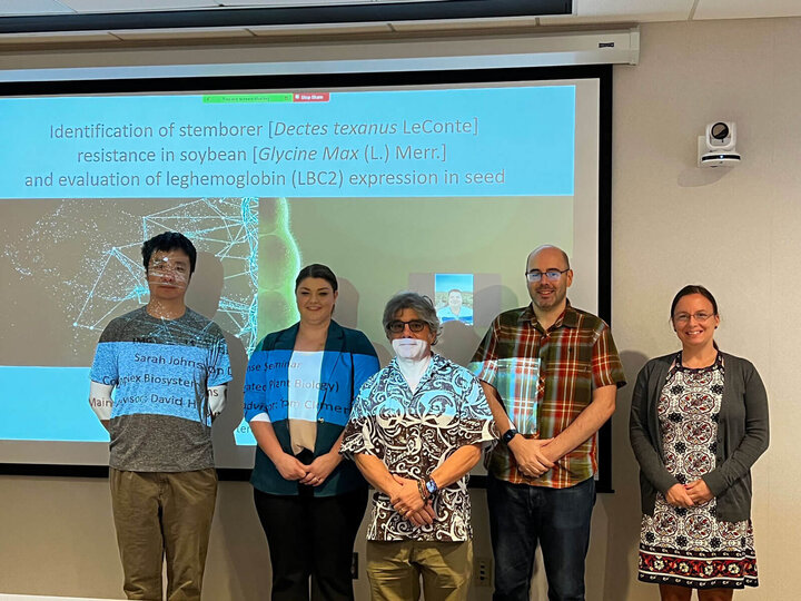 A group of people standing at the front of a classroom after a dissertation defense.